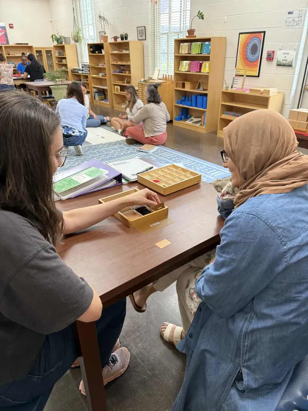 Adults working together with Montessori materials at a classroom table.